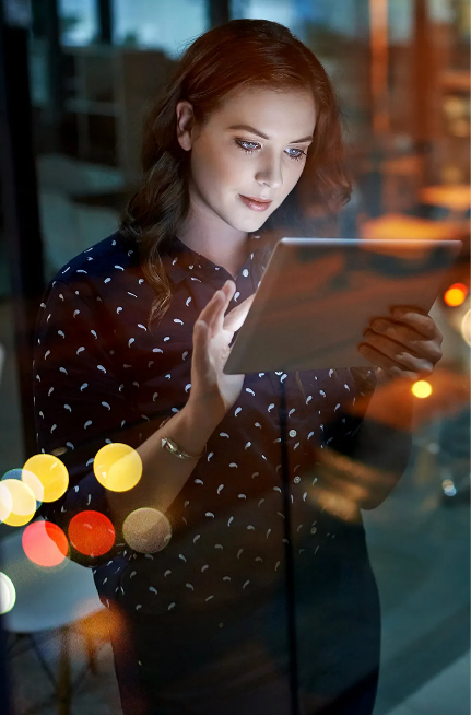 A woman is looking at her tablet in the dark.