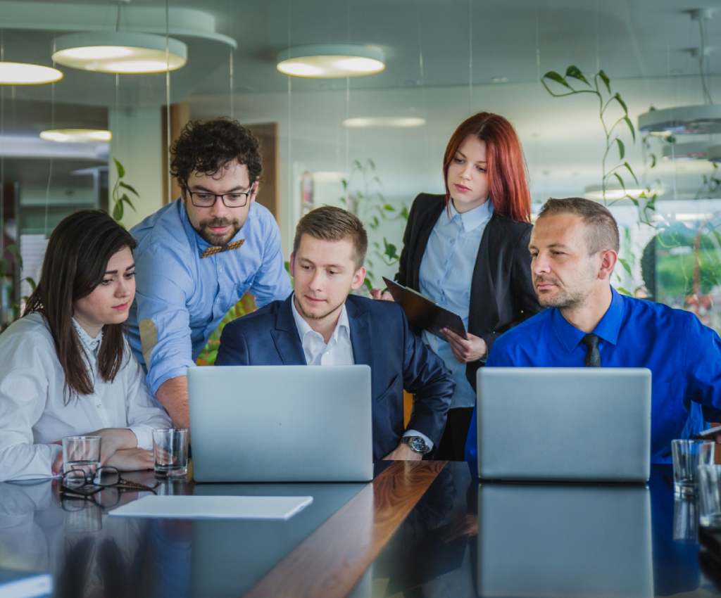 A group of people sitting at a table with laptops.