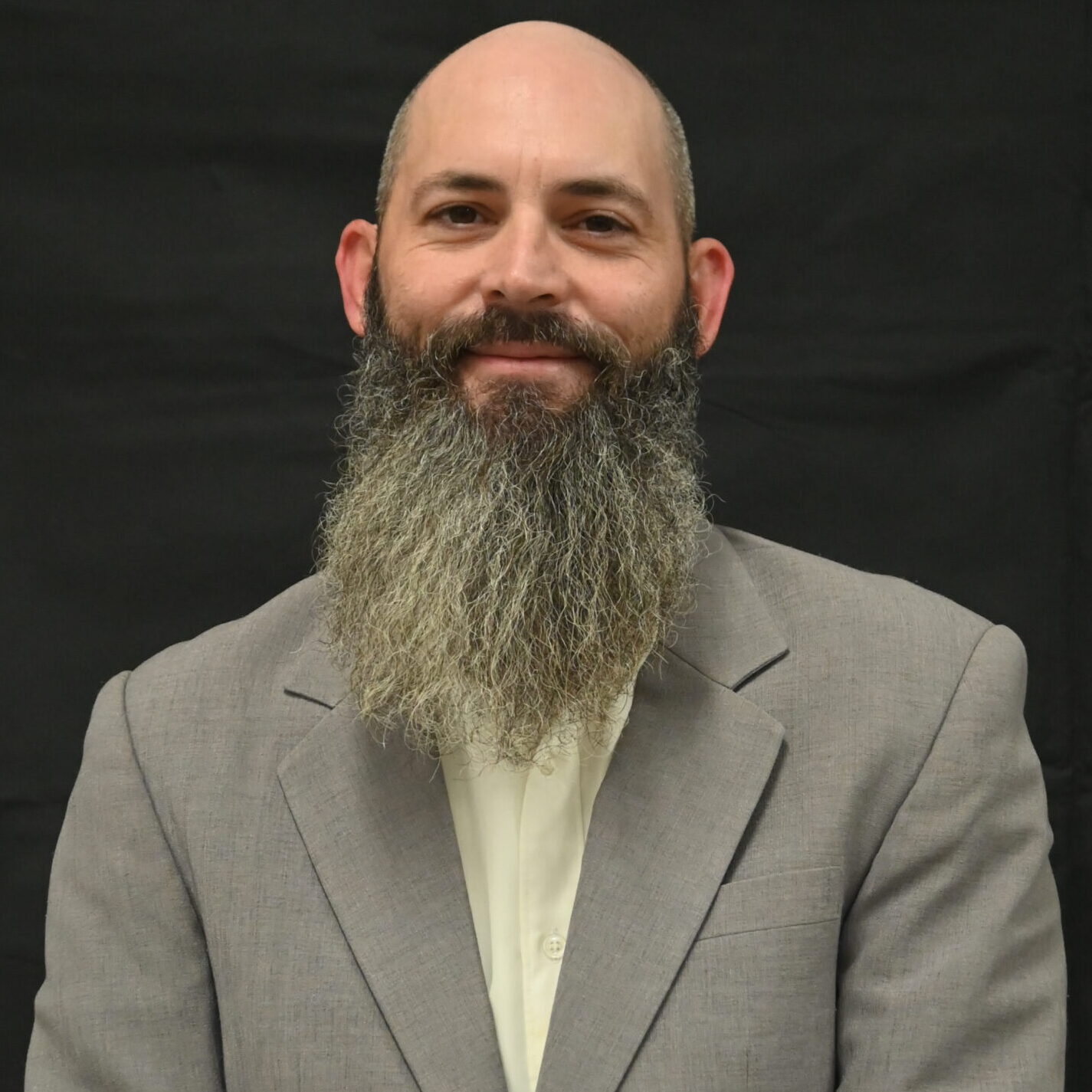 A bald man with a beard and suit jacket.