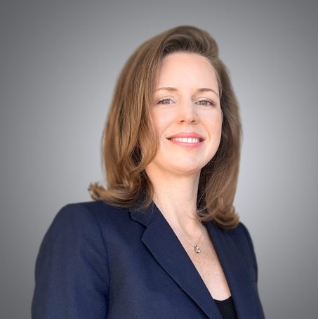 A woman in a suit and tie smiling for the camera.